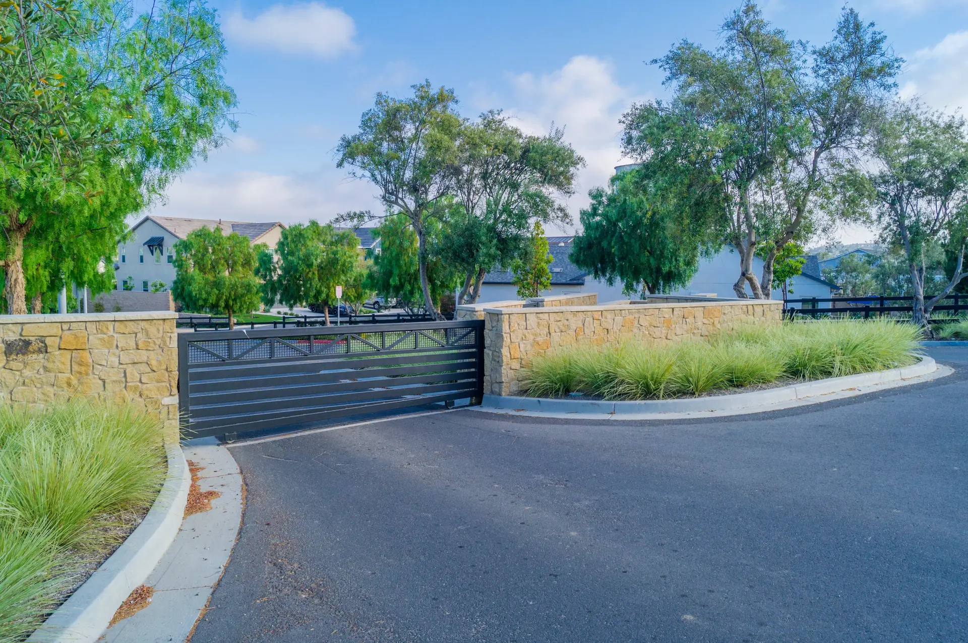 A sliding iron gate between stone walls at the entrance of a residential community